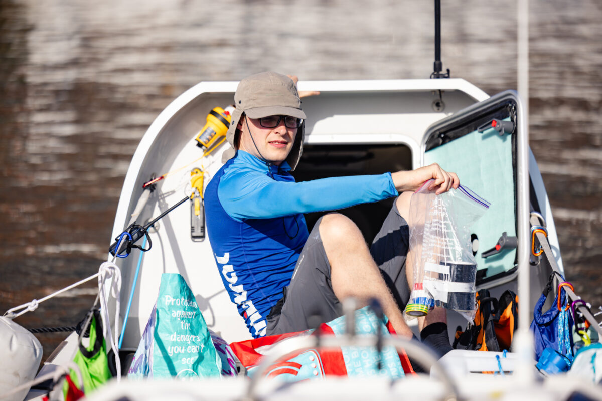 Man in blue shirt on row boat surrounded by supplies