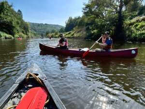 View from a canoe on a river looking two people paddling in a different canoe