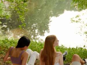young people sat by a calm river