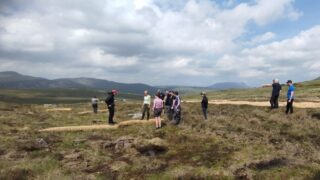 Wide view of a peatland landscape with people scattered across it