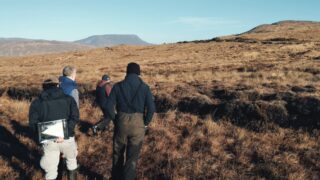 Four people stood on peatland looking across the landscape