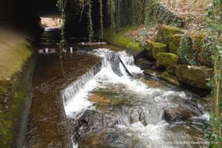 River rushing down ledges and rocks under a bridge