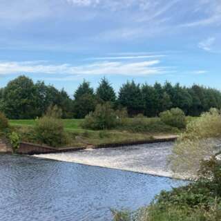 View down a river with water running over a weir
