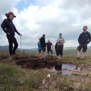 View of people around a pool of water on a peatland