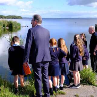 A view from the back of a group of school children and an adult looking at a river