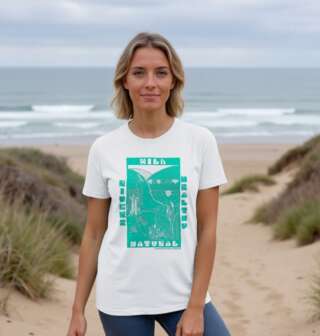 A smiling woman wears a white tee with bold turquoise design at the beach