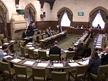 parliamentarians sit around a curved table in a long room