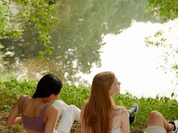 young people sat by a calm river