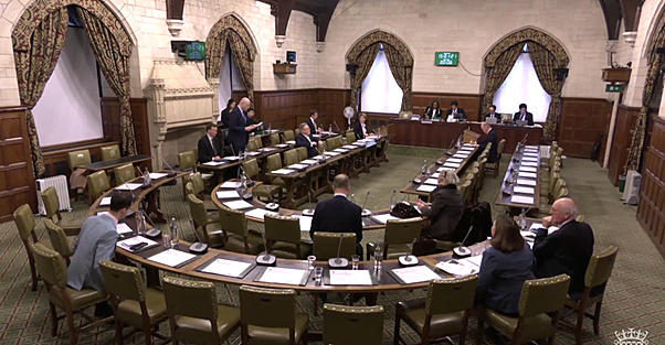 parliamentarians sit around a curved table in a long room