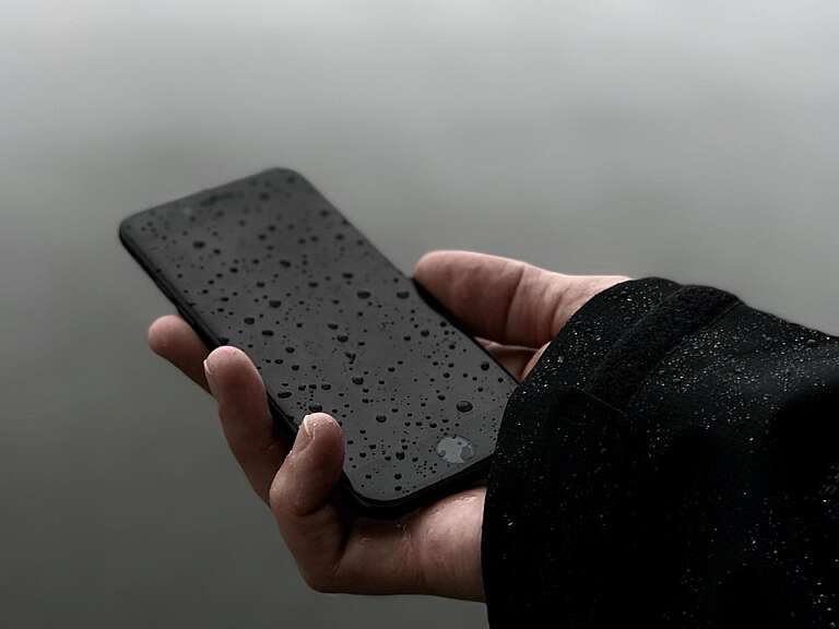 mobile phone held in a right hand outside in light rain