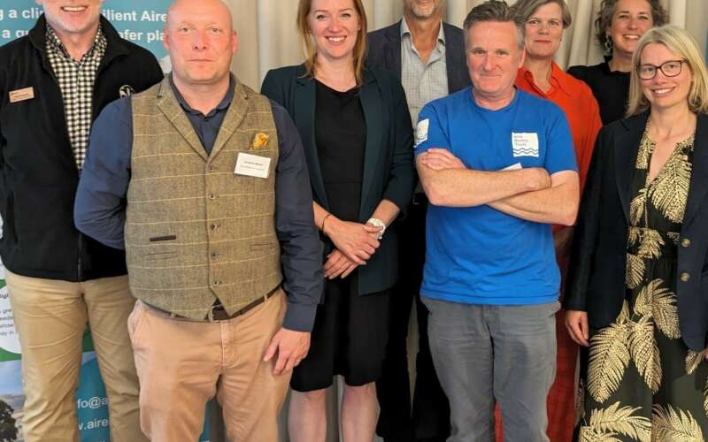 Group of people stood in front of a poster at the launch event