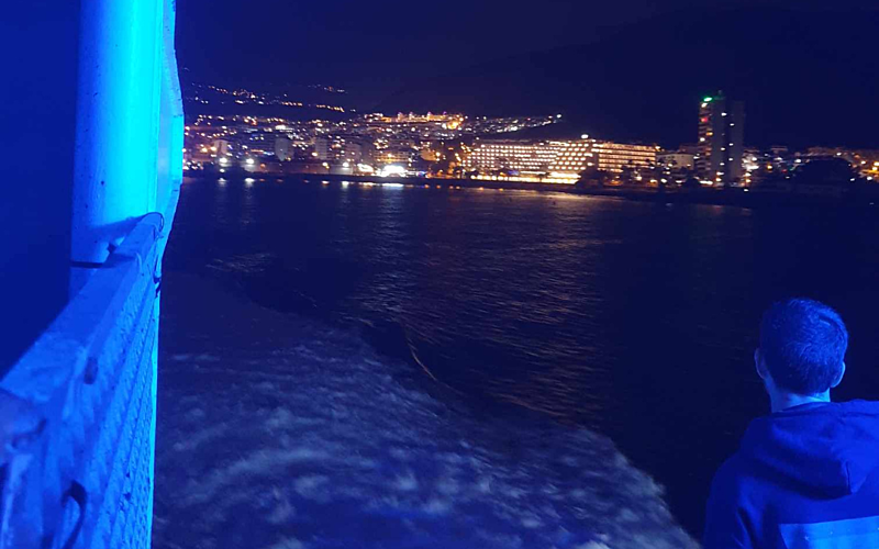 Night photo of water and buildings up ahead form a ferry