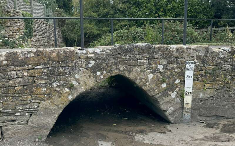 a bridge over a dried up river is shown with a height marker to one side