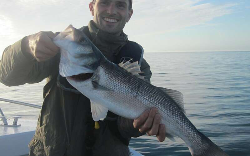 A smiling man holds a large fish up to the camera