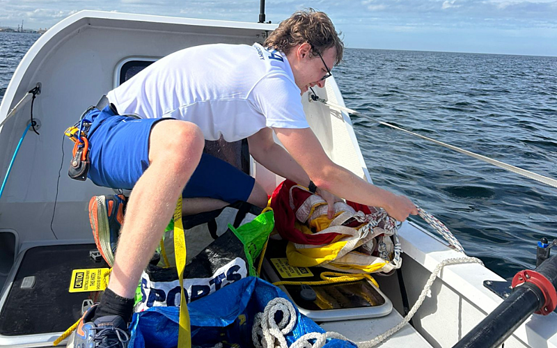 Man in white t-shirt and blue shorts on a rowing boat on the water