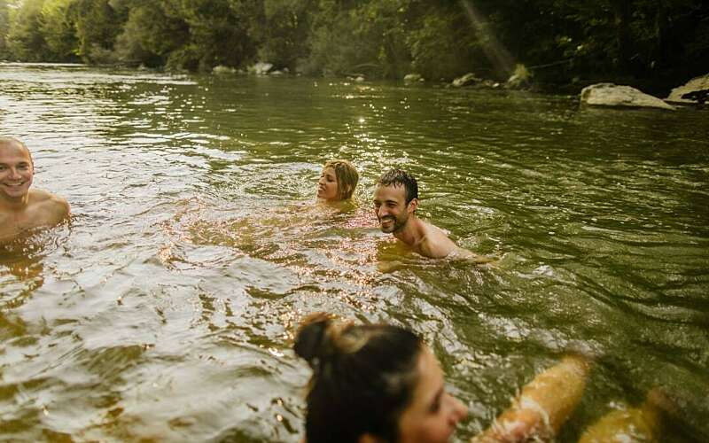 A group of friends swim happily in a green river