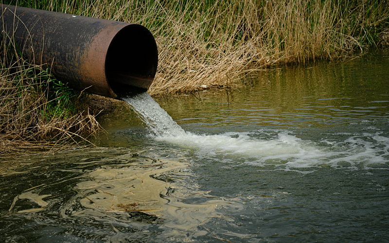 Pipe overhanging a river with water pouring out into river
