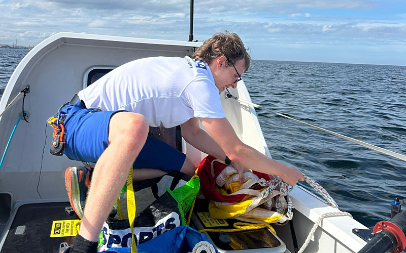 Young man in white t-shirt and blue shorts on rowing boat on the sea