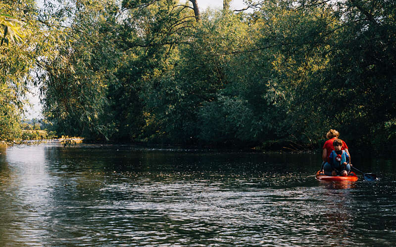 Mother and son paddle boarding a long a river