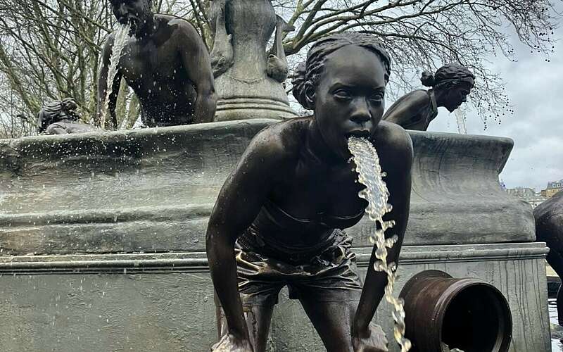 A bronze statue of a girl bent over, with water flowing from her mouth as if being sick, highlighting the issue of sewage in watercourses