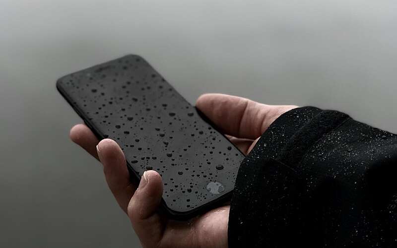 mobile phone held in a right hand outside in light rain