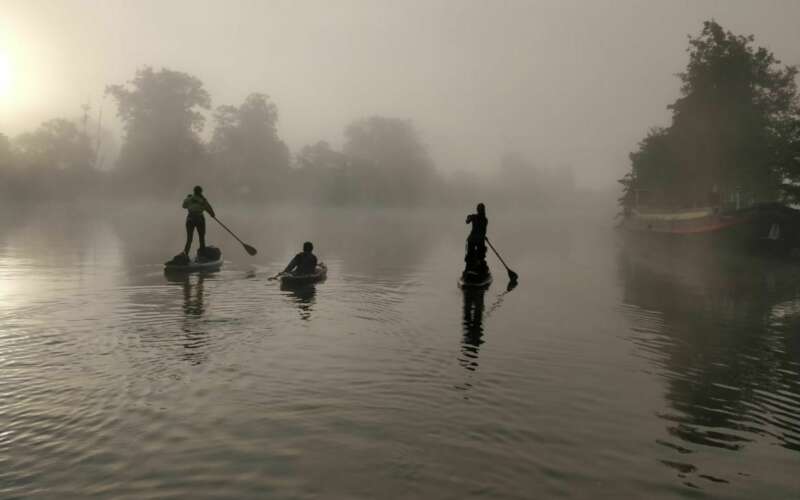 two paddle boarders and kayaker on river