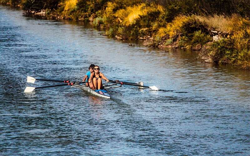 Two rowers are out on a rowing boat in the late evening sun on a river