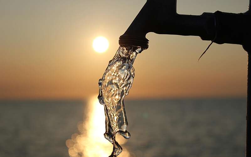 water flows from an outside tap against a sunset