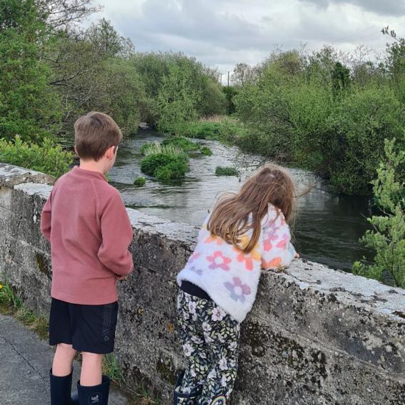 Kids looking over a bridge by a river
