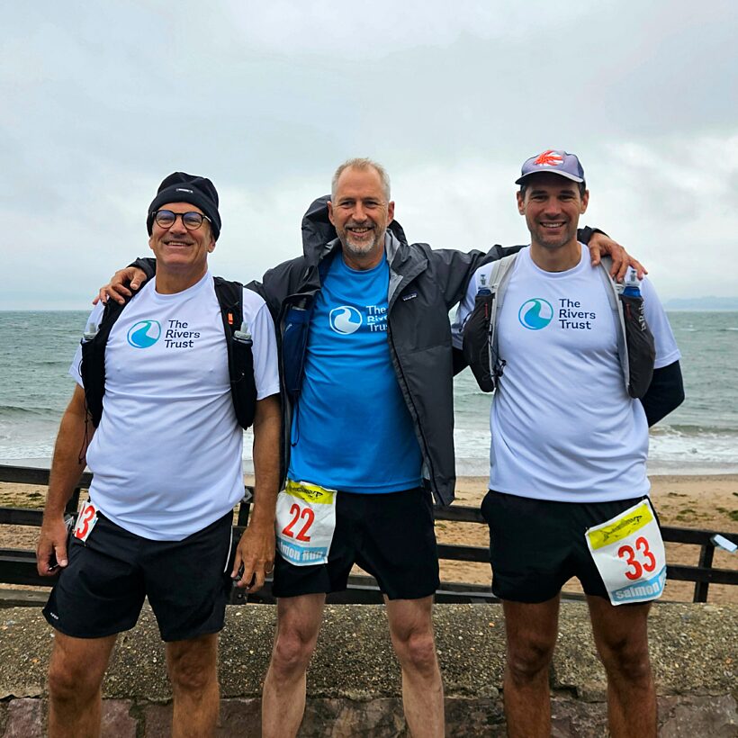 Three male runners stood on the beach before start of race