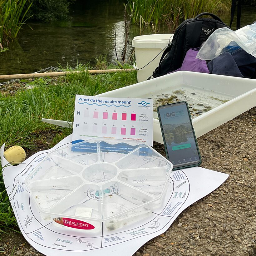 A phone displaying Big River Watch leaning against a white tray with river water