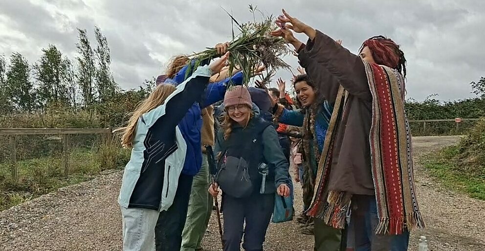 a smiling woman walks through an arch of arms held up by a welcome party at the end of her walk