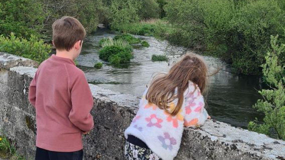 Kids looking over a bridge by a river