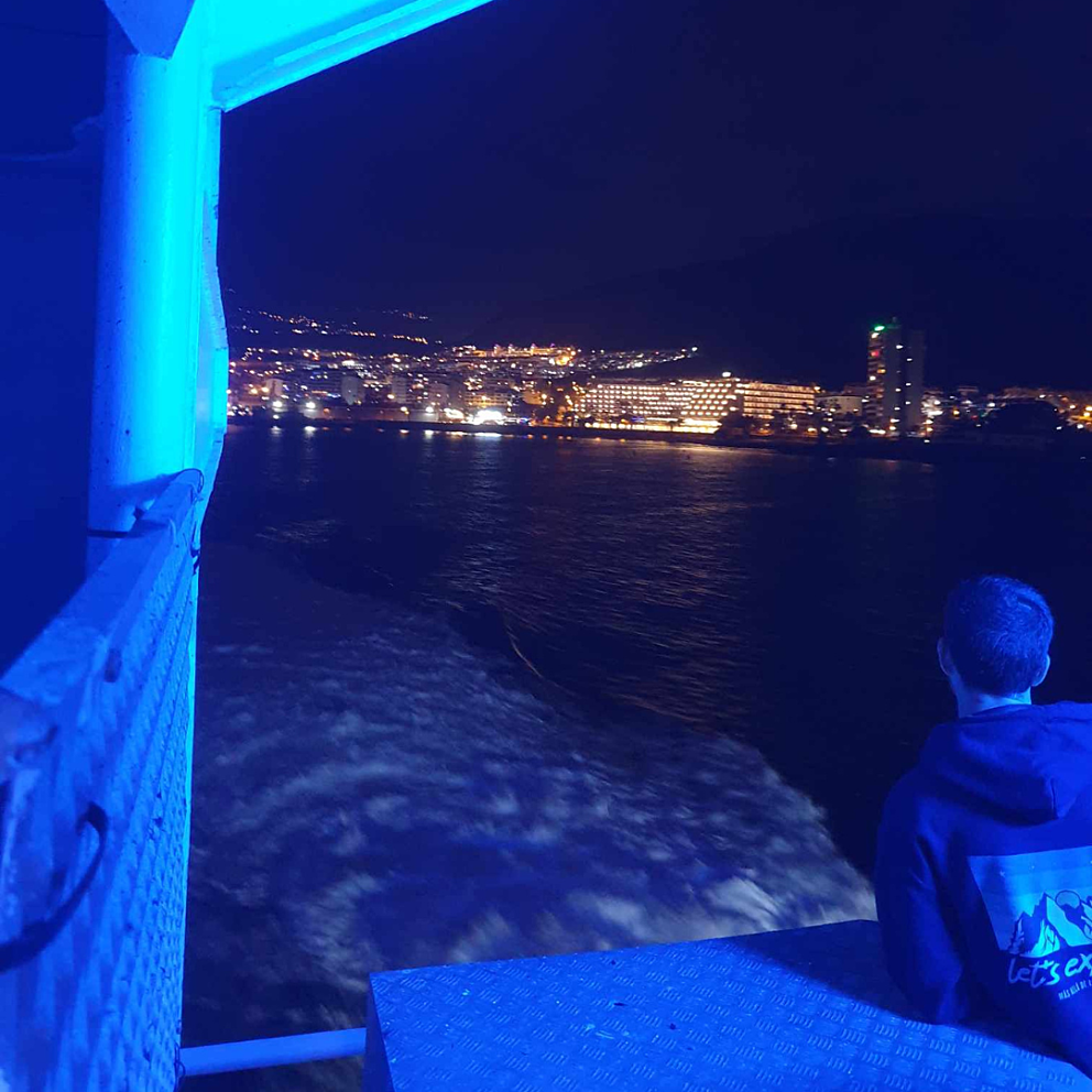 Night photo of water and buildings up ahead form a ferry
