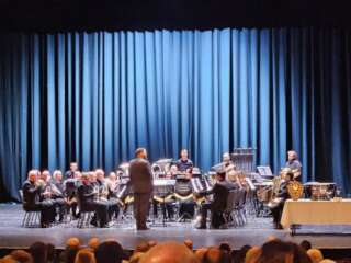 A photograph of Allerton Brass on stage in front of a blue curtain