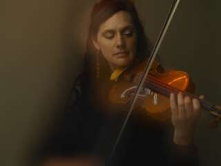 An photograph with a hazy effect of a woman with brown hair playing the violin
