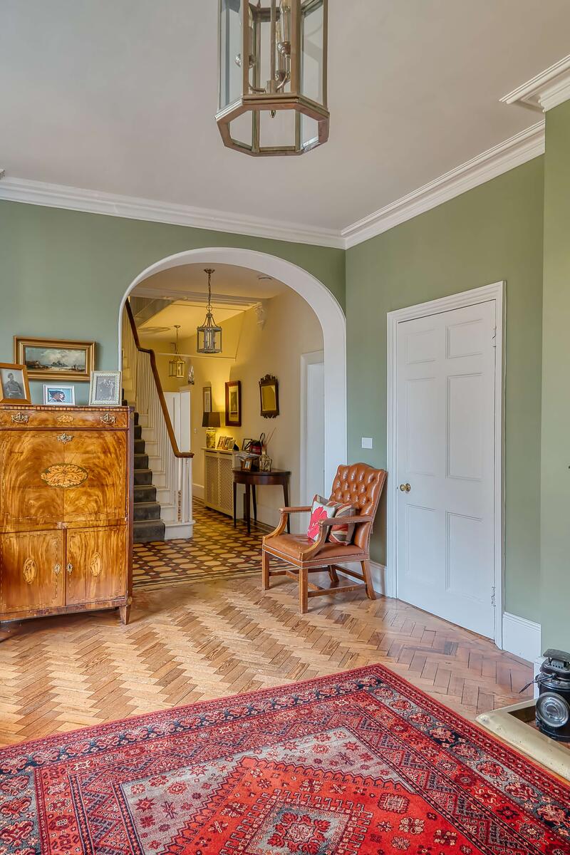 Period entrance lobby with green walls, parquet floor, fireplace and arched hallway entrance