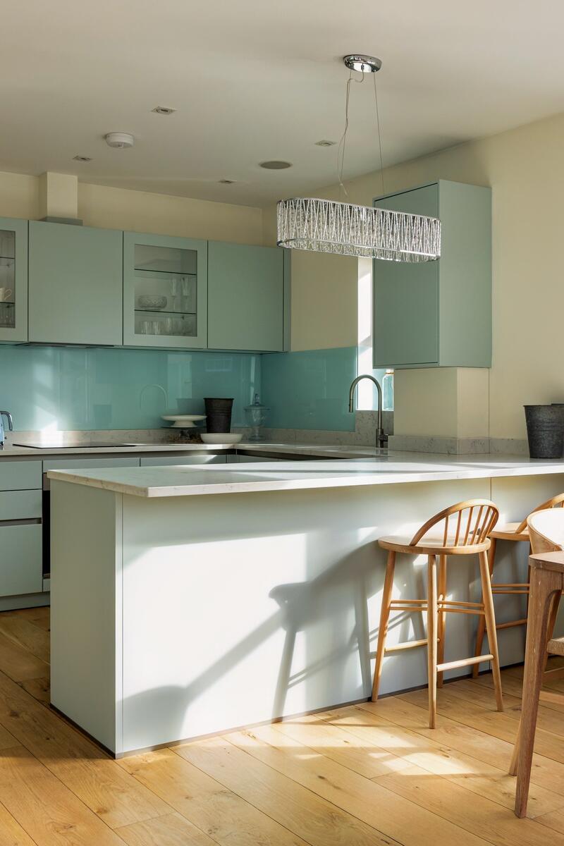 Bright dual-aspect open plan kitchen and living space in modern Richmond apartment with pale cabinetry, timber flooring and natural light.