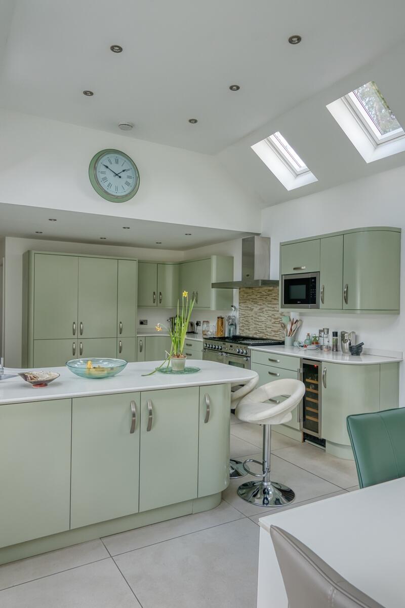 Large extended 1930s kitchen with vaulted ceiling, Velux skylights, mint green cabinetry and central island in Arts and Crafts home