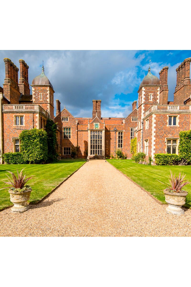 Grand Grade I listed Elizabethan country house with red brick façade, formal gardens and symmetrical architecture.