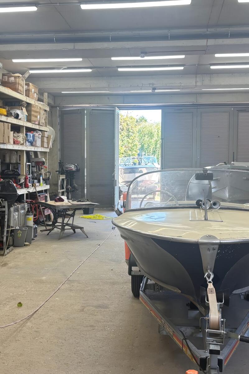 Working boatyard workshop with boat storage, industrial shelving and maintenance equipment.