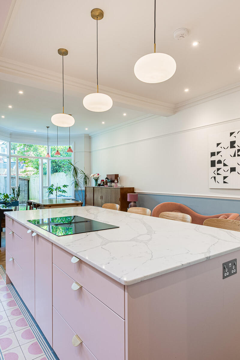 Dining 1 Open-plan kitchen and dining room with blush pink cabinetry, large island, rooflights and herringbone flooring.