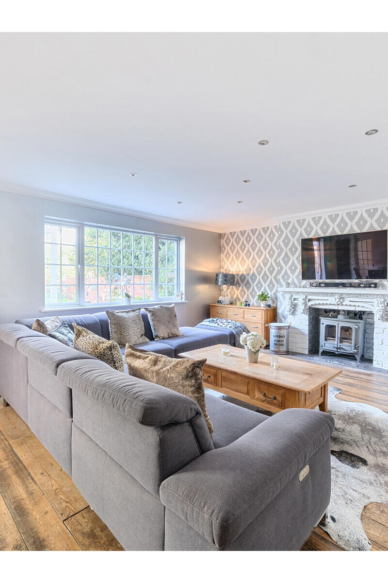 Spacious open-plan sitting and dining room with timber flooring, fireplace and large windows