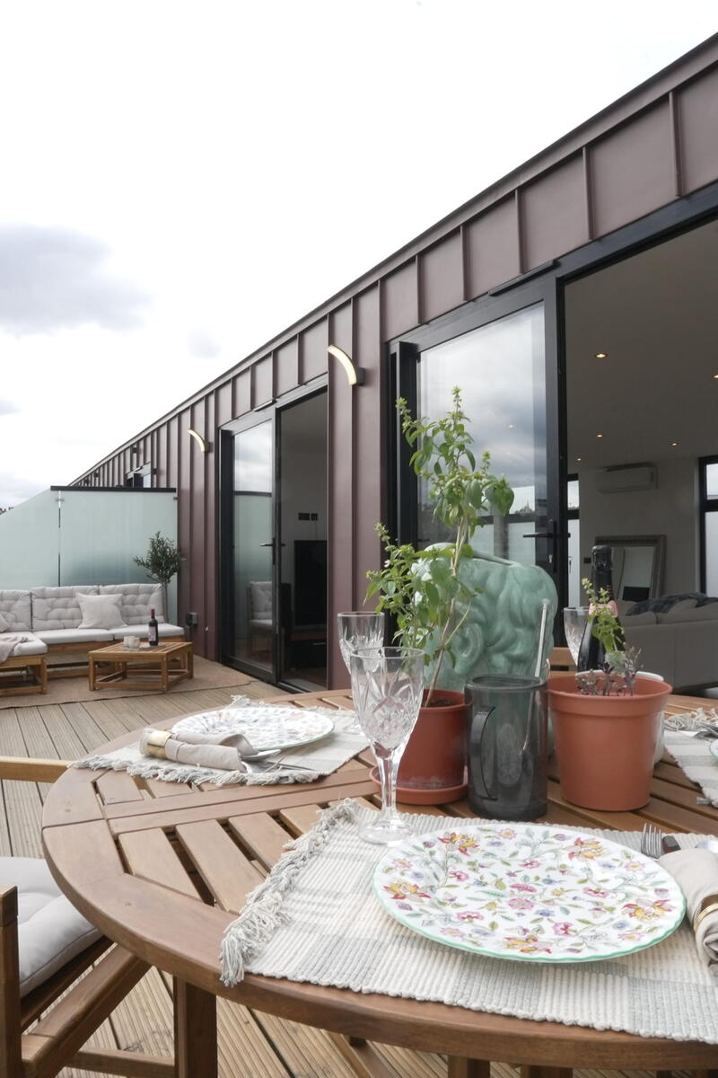 Large private roof terrace with dining and seating areas, glass balustrade and direct access to the penthouse living space.
