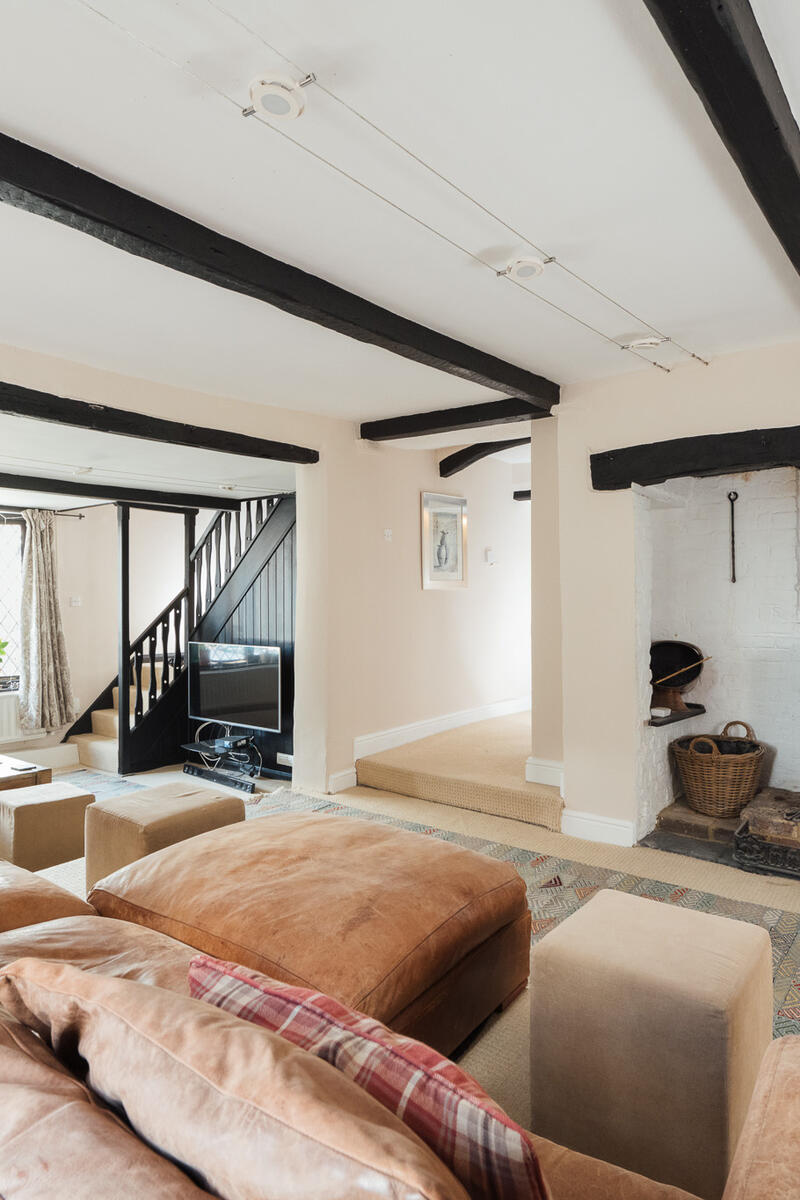 Traditional cottage living room with exposed beams, leaded windows, wood-burning stove and characterful period features, ideal for film and photography.
