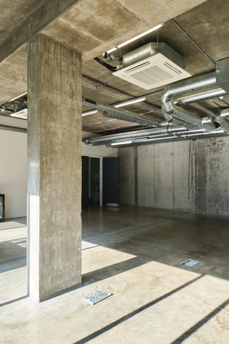industrial-style photography studio with exposed concrete pillars, polished floors, and ductwork ceiling in East London