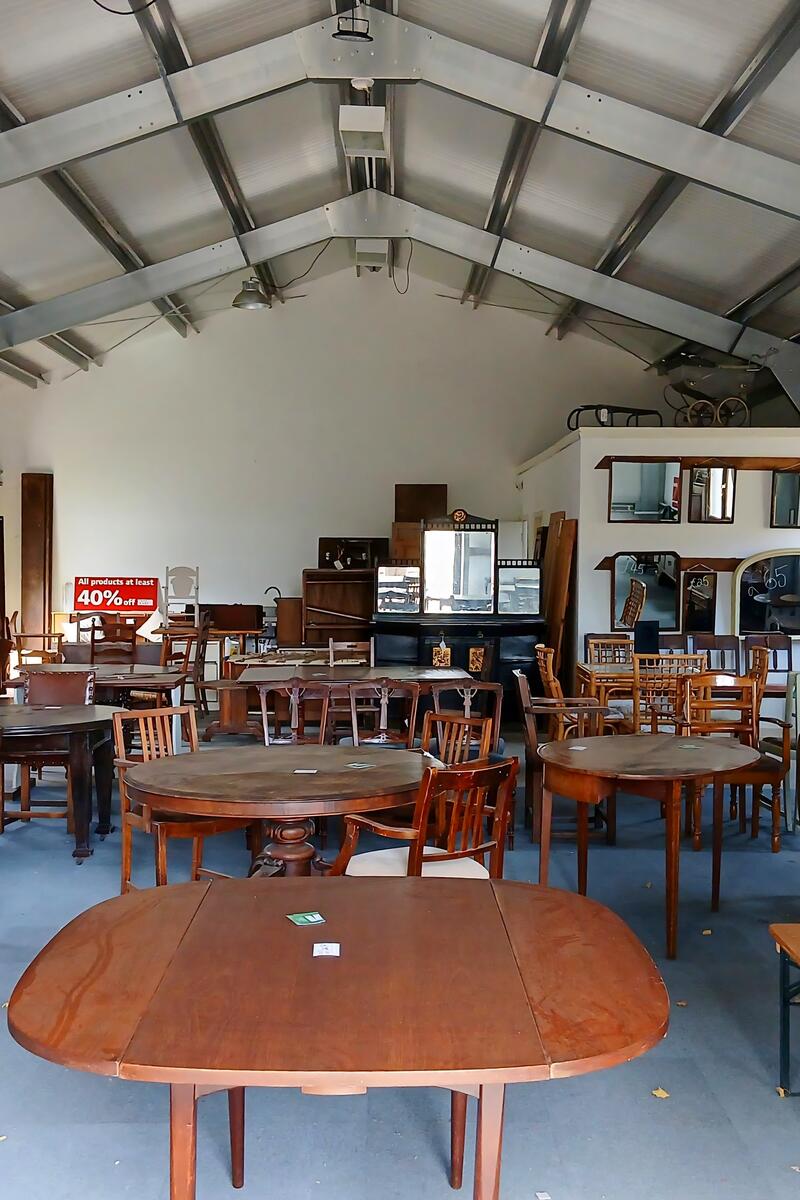 Interior of a large industrial barn in Leighton Buzzard, filled with vintage wooden tables and chairs, available as a filming location.