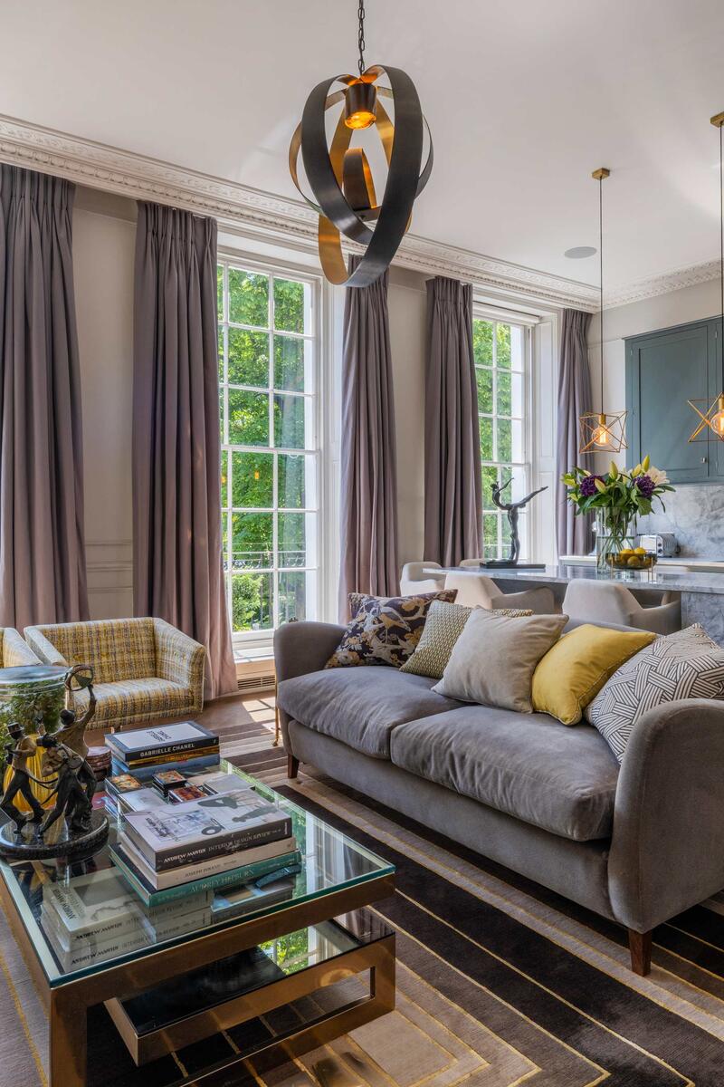 Open-plan living space with marble kitchen island, pendant lighting, large sash windows and contemporary decor in Dorset Square Marylebone apartment