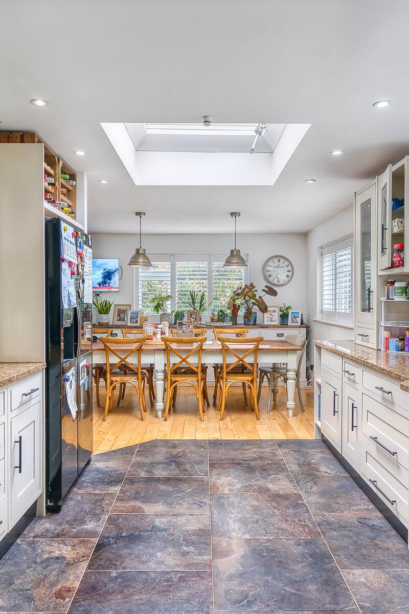 Bright open plan kitchen and dining area in Hertfordshire family home, featuring cream shaker-style units, granite worktops, skylight and wooden dining table — ideal for TV commercials and family film shoots.