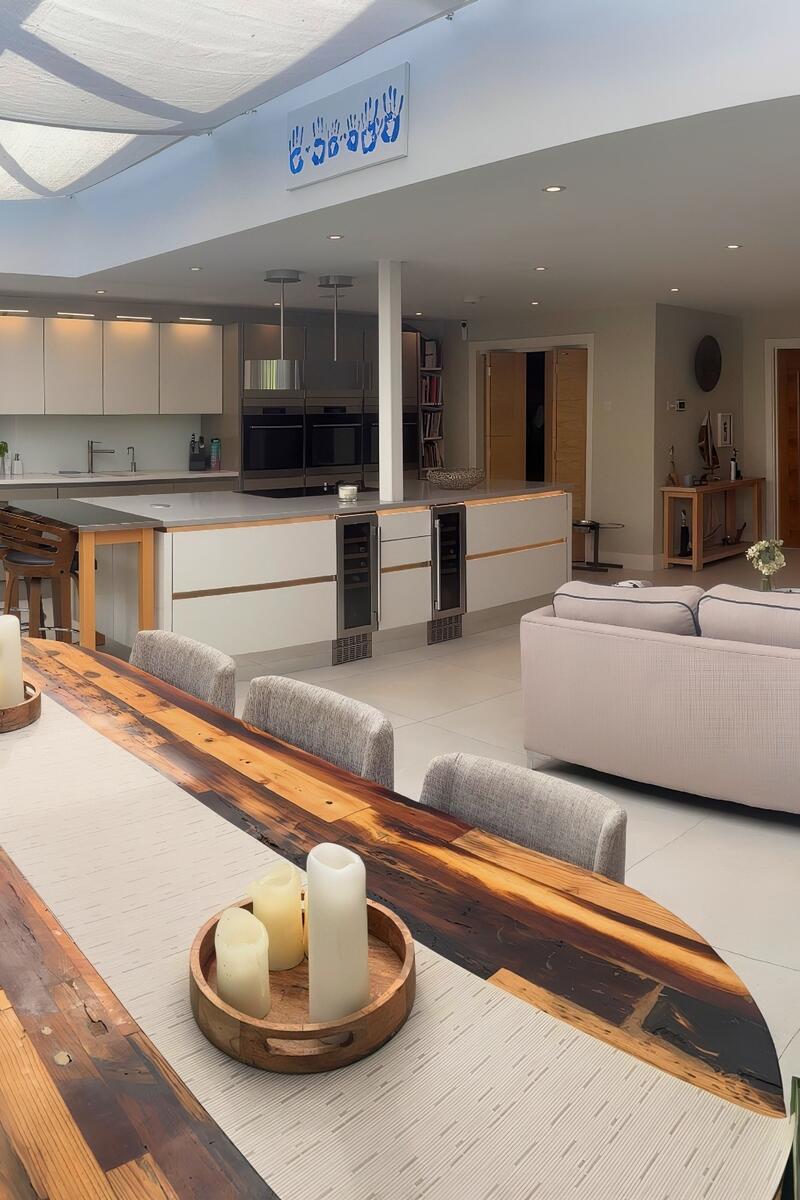Spacious open plan kitchen, dining and living area with large skylight, modern cabinetry, island breakfast bar, and contemporary seating in neutral tones.